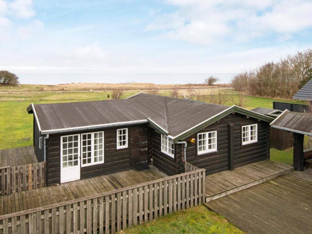 a log cabin with a deck and a fence at 6 person holiday home in Grenaa in Grenå