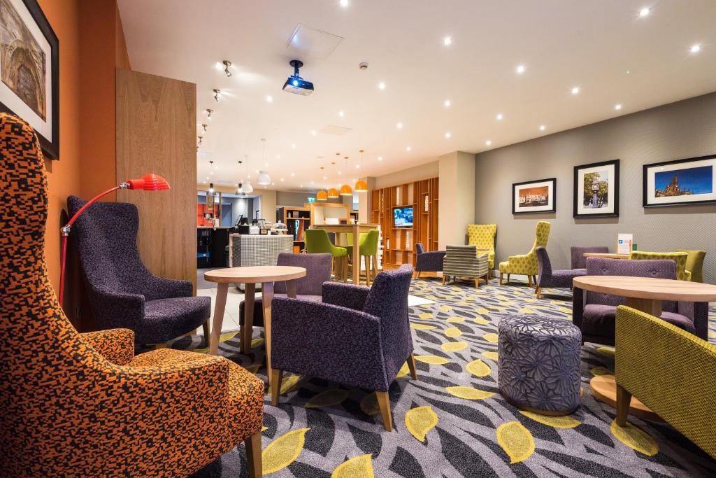 a waiting room with chairs and tables in a hotel at Holiday Inn Rotherham-Sheffield M1,Jct.33 by IHG in Rotherham