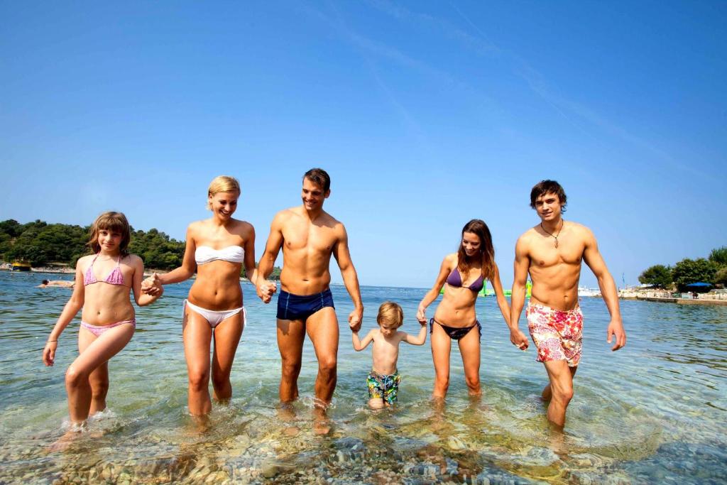 a group of people standing in the water at the beach at Hotel Istra Plava Laguna in Poreč