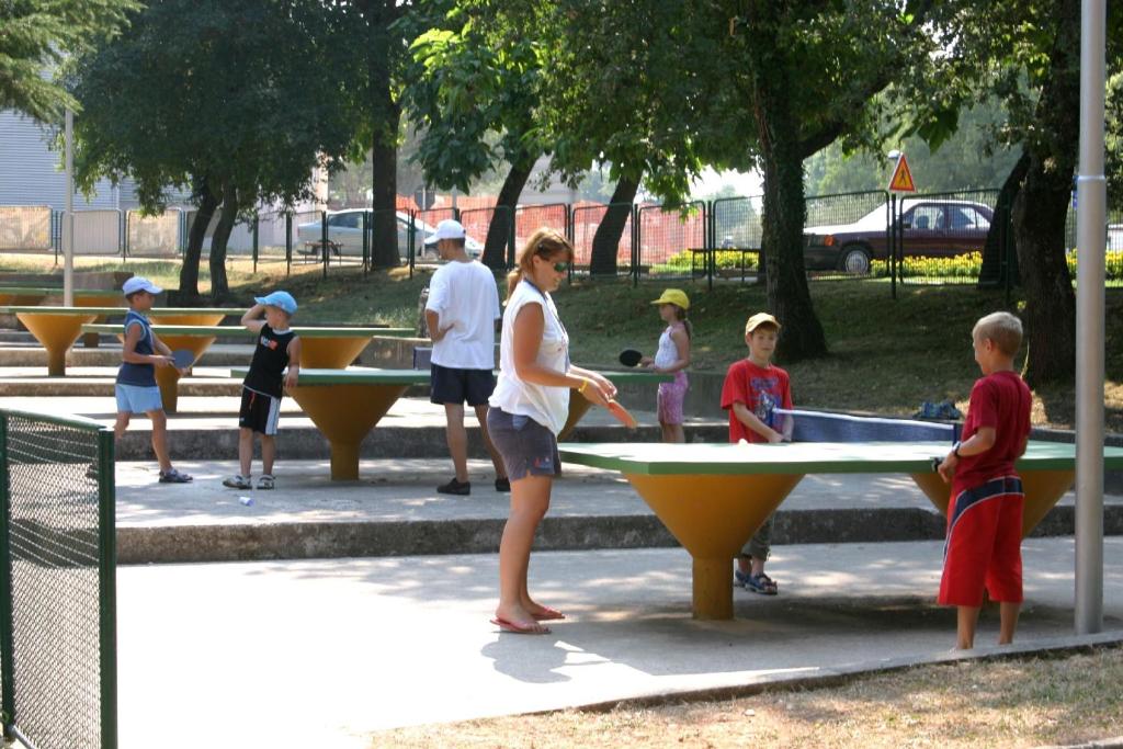 a woman playing ping pong in a park with children at Hotel Istra Plava Laguna in Poreč
