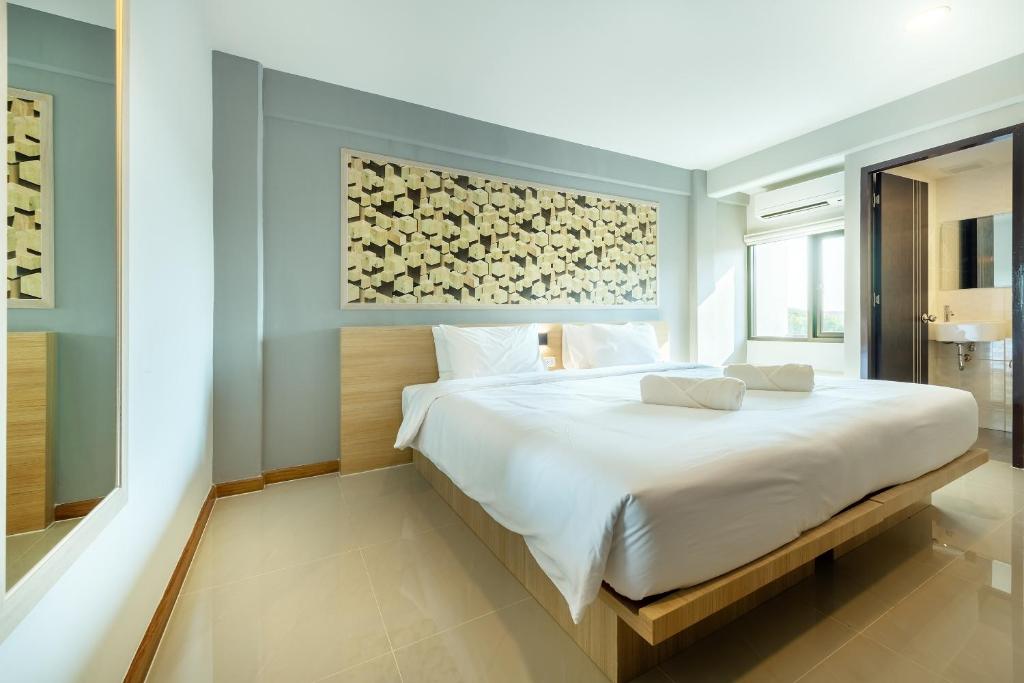 羅勇的住宿－PLAAI Play Hotel，卧室配有一张白色大床,墙上挂有绘画作品