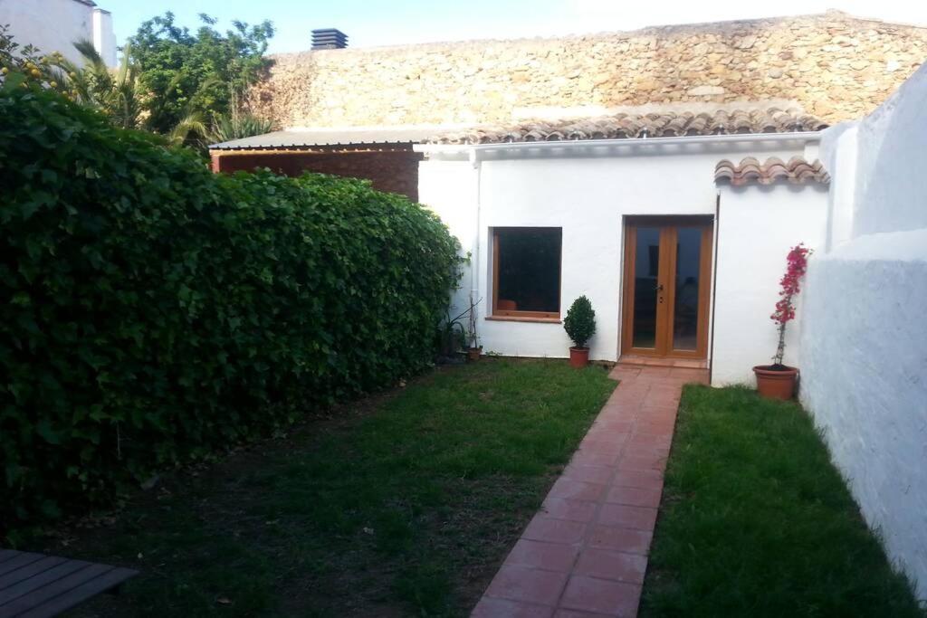 a white house with a door and a yard at La casita marrón in Palafrugell