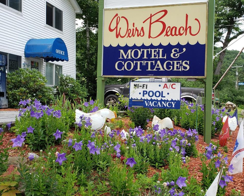 Un letrero para un motel y cafeterías con flores. en Weirs Beach Motel & Cottages, en Weirs Beach