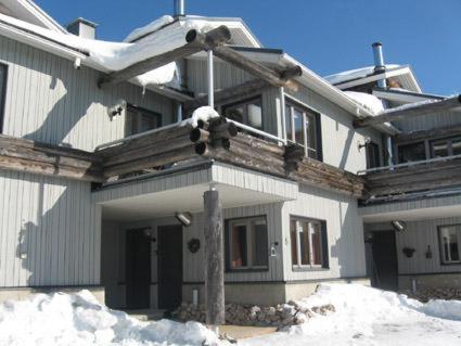 una casa con nieve en el suelo delante de ella en Rukapahta, en Kuusamo