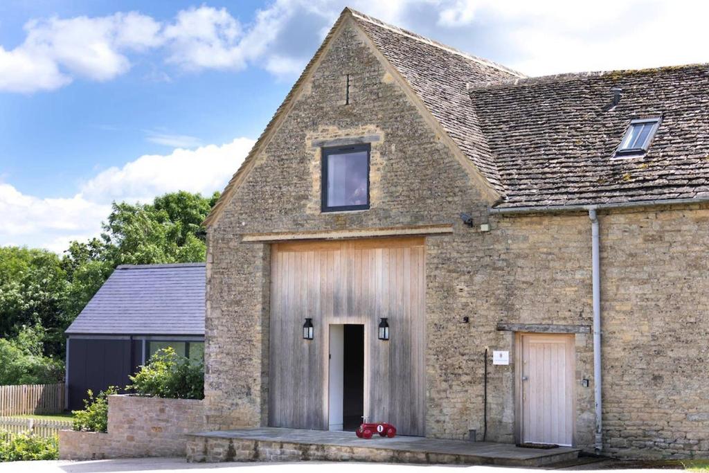 an old brick house with a wooden garage at Crucis Park Estate in Cirencester
