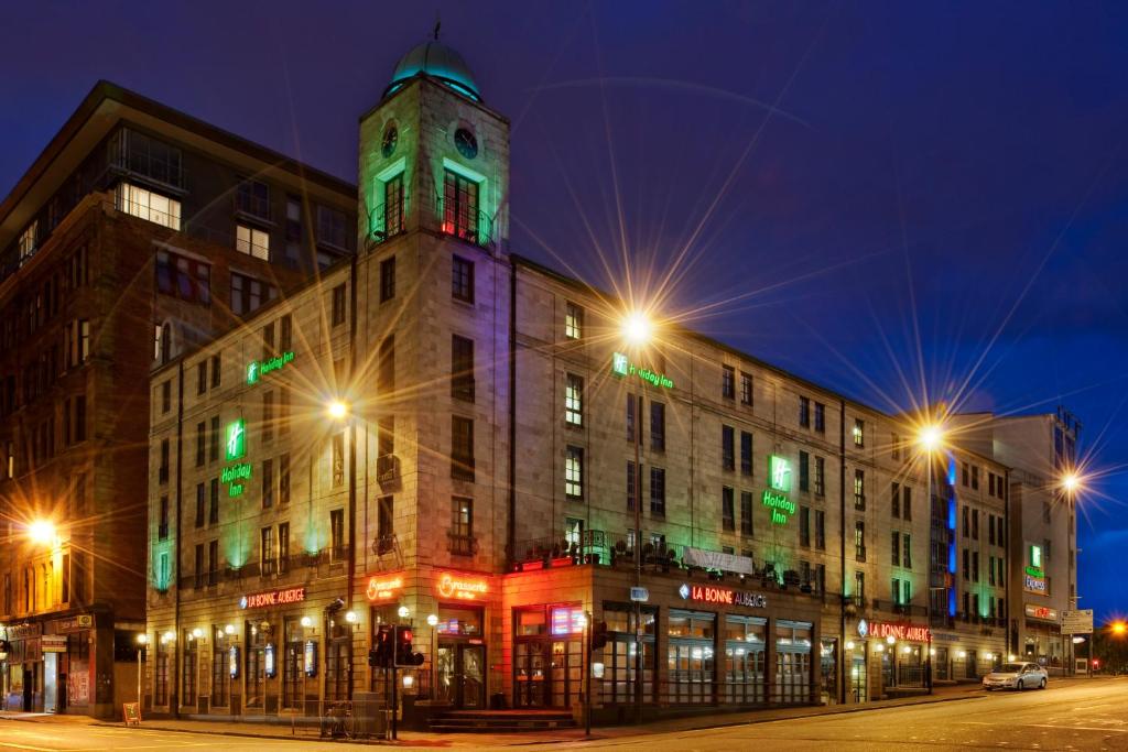 a building with a clock tower at night at Holiday Inn Glasgow City Theatreland by IHG in Glasgow