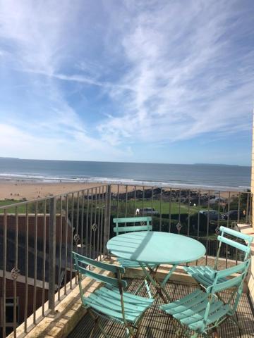 a table and chairs on a balcony with the beach at Woolacombe Seaside Apartment in Woolacombe