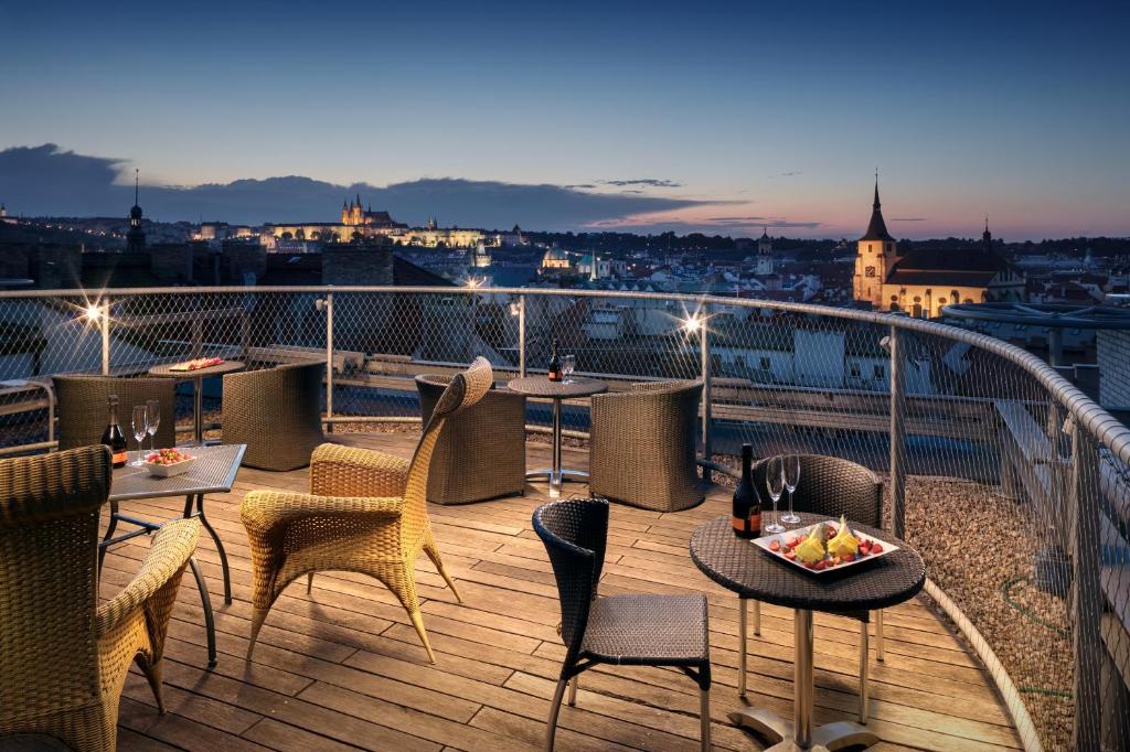 a balcony with tables and chairs and a view of a city at Design Metropol Hotel Prague in Prague