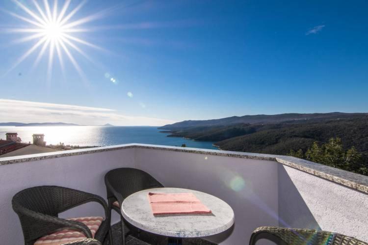 una mesa y sillas en un balcón con vistas al agua en Luna, en Rabac