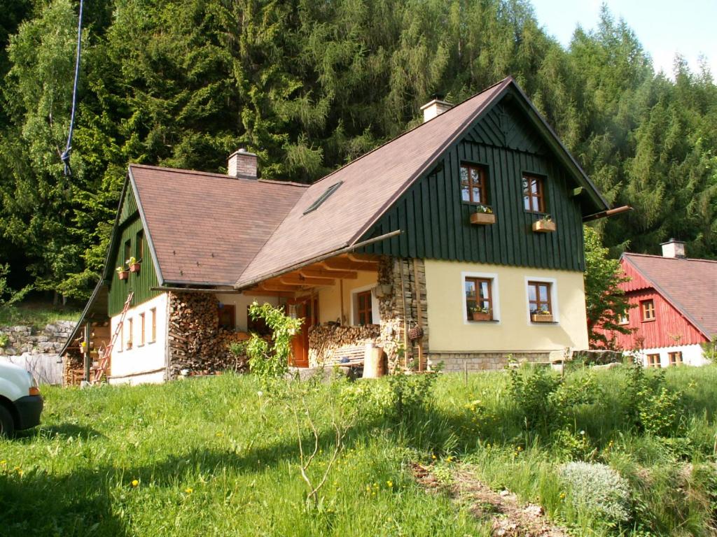 una casa verde y blanca en un campo con árboles en Privat No. 2, en Adršpach