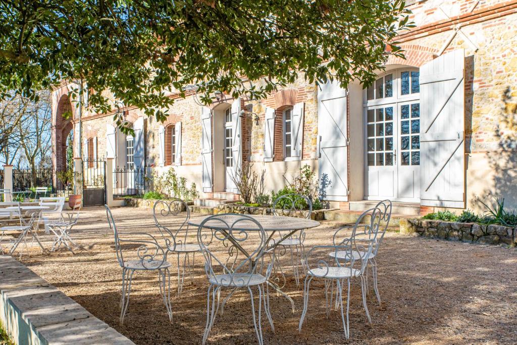 une table et des chaises devant un bâtiment dans l'établissement Les Nuits du Pastelier, à Teulat