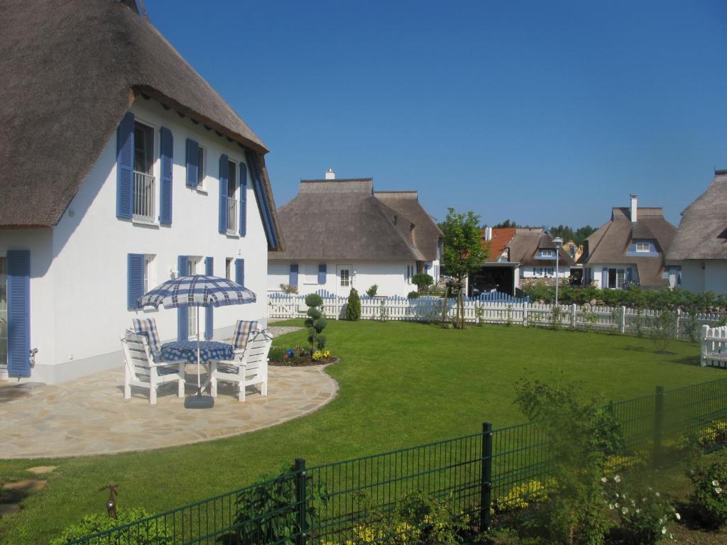 a house with a yard with chairs and an umbrella at Ferienhaus „Sonneninsel“ in Ostseebad Karlshagen