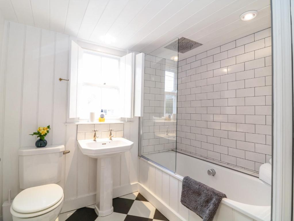 a white bathroom with a sink and a toilet and a tub at 1 Jubilee Cottage in Tintagel