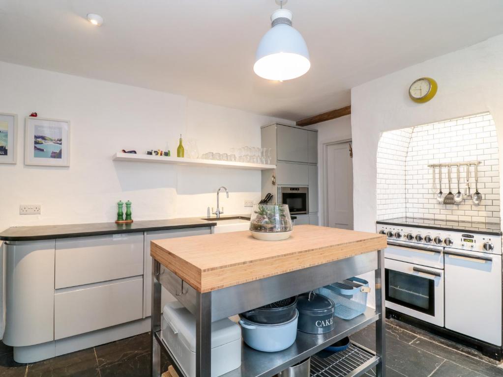 a kitchen with white cabinets and a wooden counter top at 1 Jubilee Cottage in Tintagel
