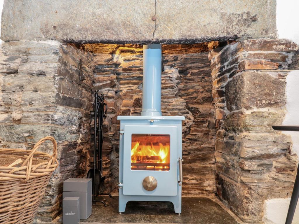 a stove in front of a stone wall at 1 Jubilee Cottage in Tintagel