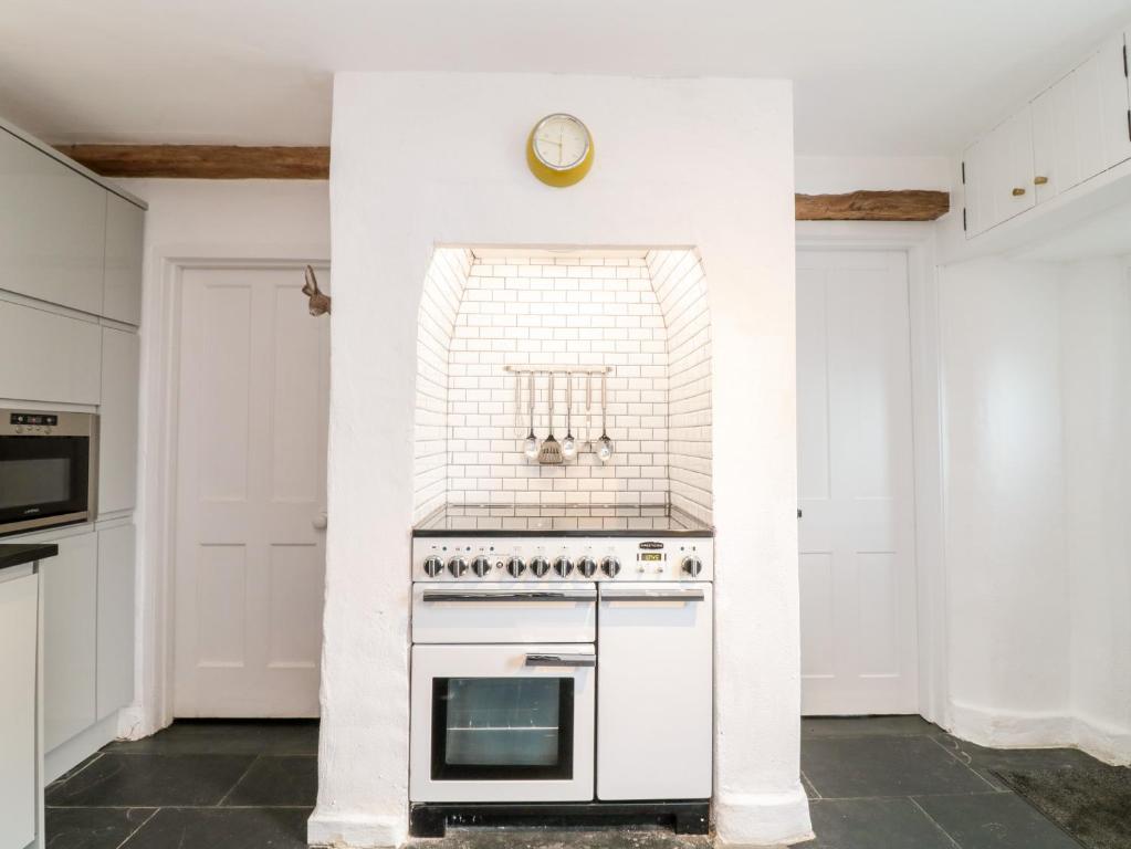 a kitchen with a stove and a clock on the wall at 1 Jubilee Cottage in Tintagel