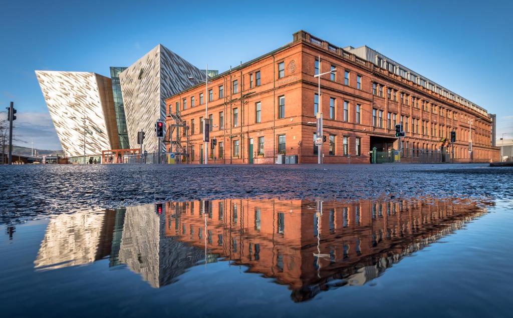 um edifício com o seu reflexo na água em Titanic Hotel Belfast em Belfast