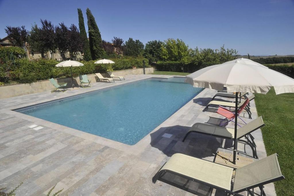 - une piscine avec des chaises et un parasol dans l'établissement Casale il Moro by VacaVilla, à Brucciano