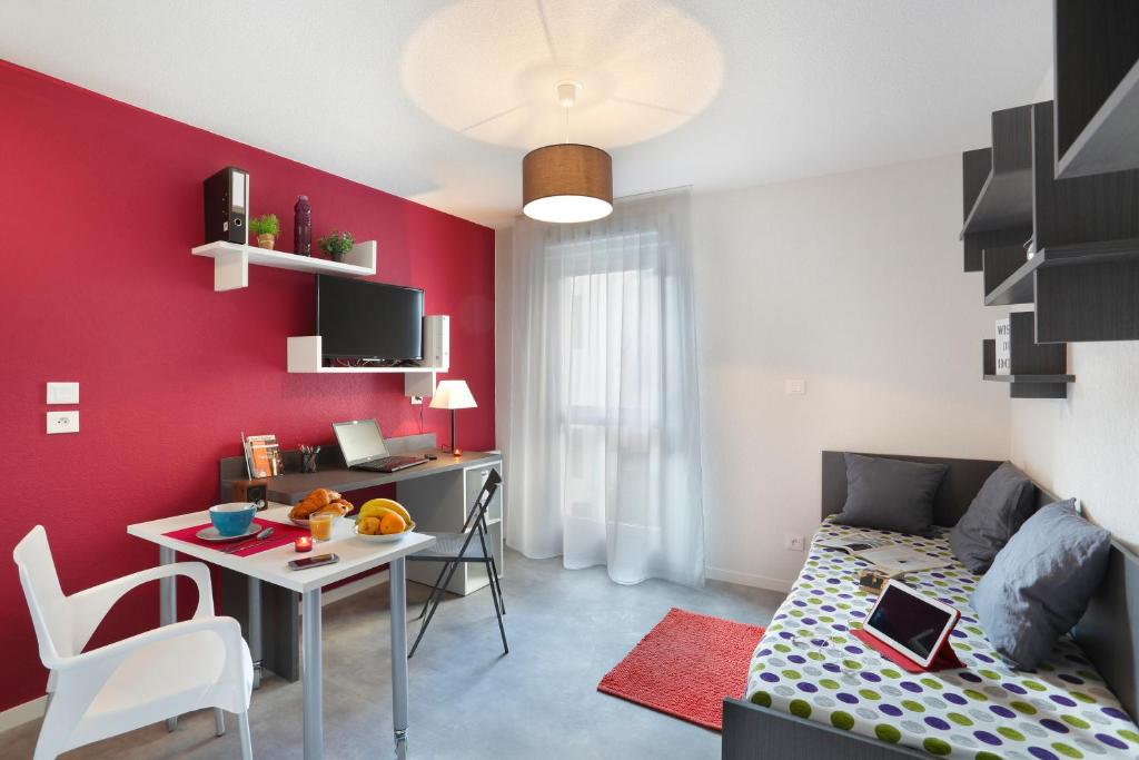 uma pequena sala de estar com uma parede em vermelho em Résidence Néméa Clermont Centre em Clermont-Ferrand