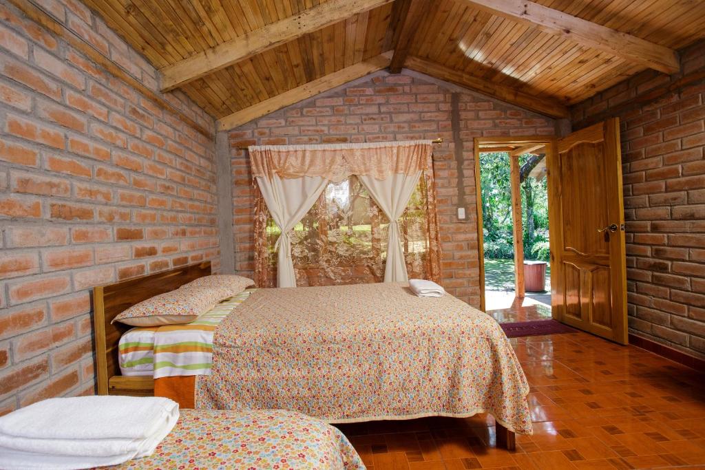 1 dormitorio con 2 camas en una pared de ladrillo en Estancia, CABAÑAS INTAG, en Vacas Galindo