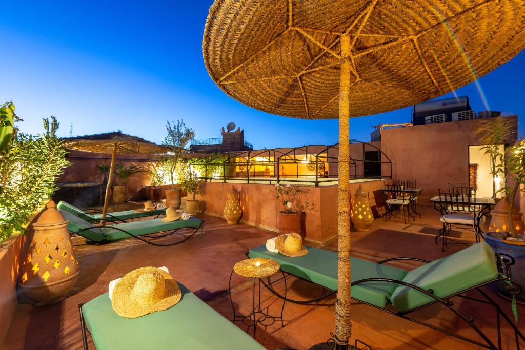 a patio with a large umbrella and chairs and tables at Riad L'orange Bleue in Marrakesh