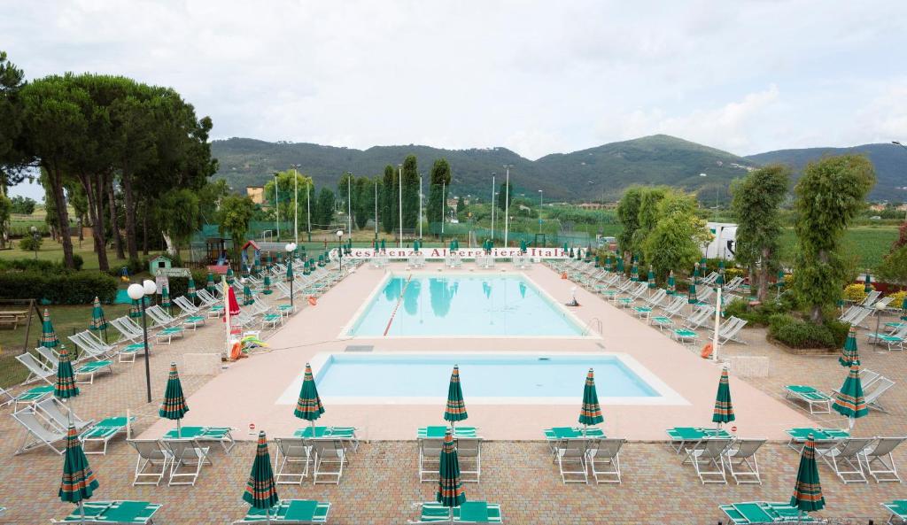 una gran piscina con tumbonas y mesas. en Residenza Alberghiera Italia, en Luni