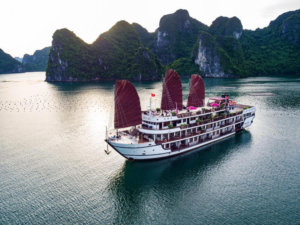 un crucero con velas rojas en el agua en Alisa Cruise Halong, en Ha Long