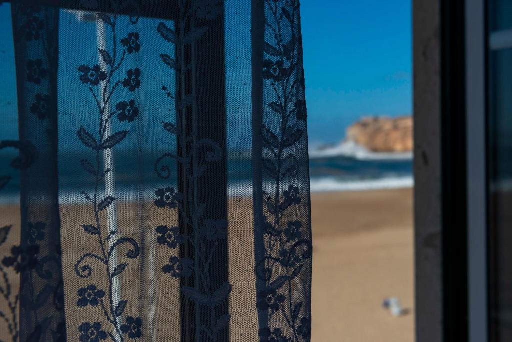 een raam met uitzicht op het strand bij DonaCamó Charming House in Nazaré