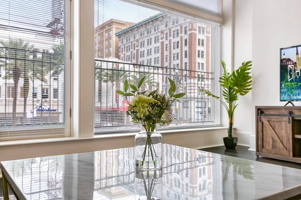 un tavolo in vetro con fiori in una stanza con finestre di 1 and 2 BR Private Condos Steps Away From French Quarter a New Orleans