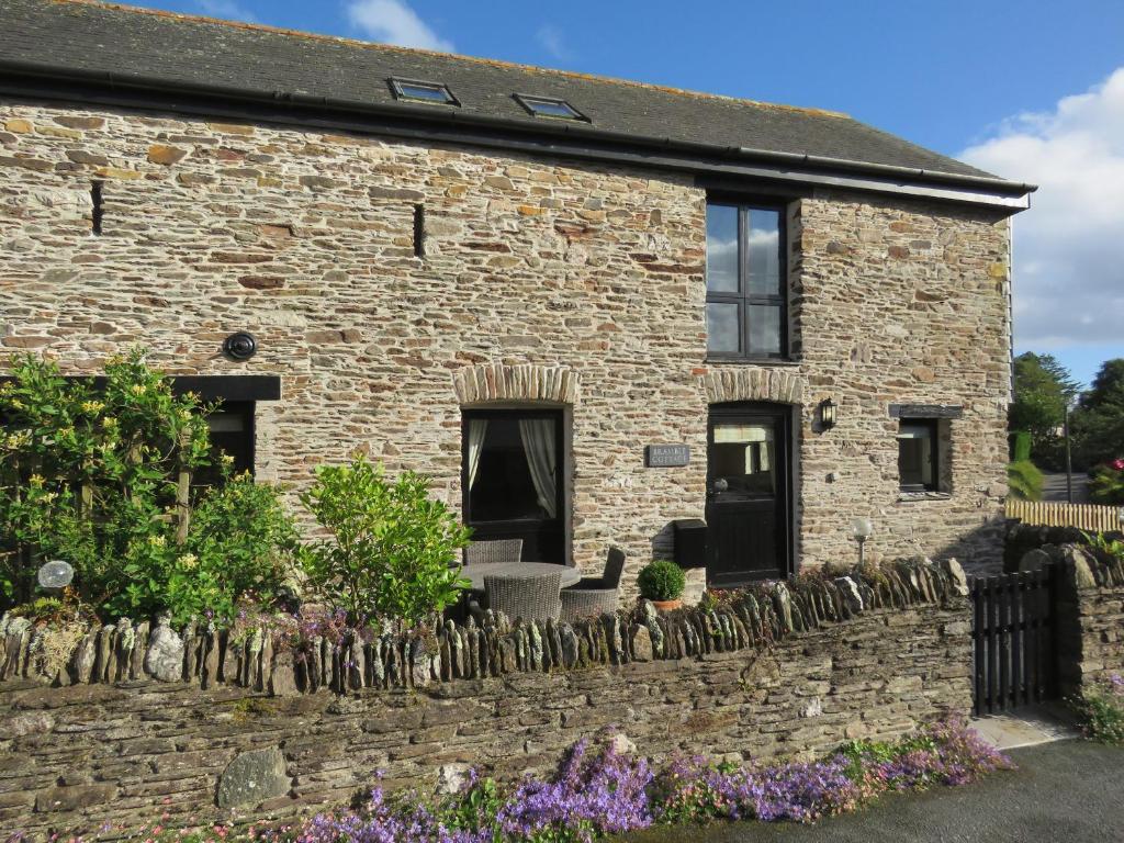 a stone house with a stone wall and flowers at Bramble Cottage in Bigbury
