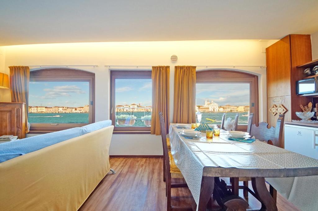 ein Wohnzimmer mit einem Tisch, einem Sofa und Fenstern in der Unterkunft DolceVita Apartments N 453 Canal View in Venedig