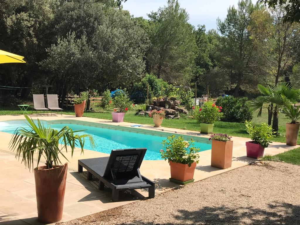 a swimming pool with a bench and potted plants at la campagne de Mari in Peyrolles-en-Provence