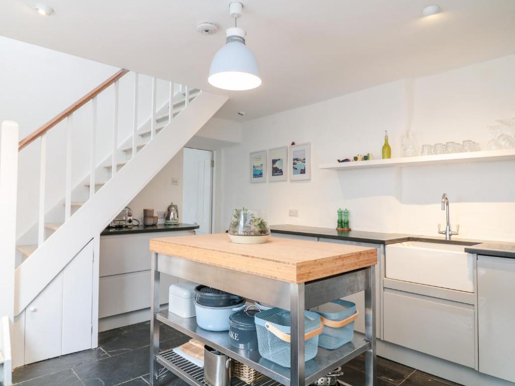a kitchen with white cabinets and a kitchen island at 1 Jubilee Cottage in Tintagel