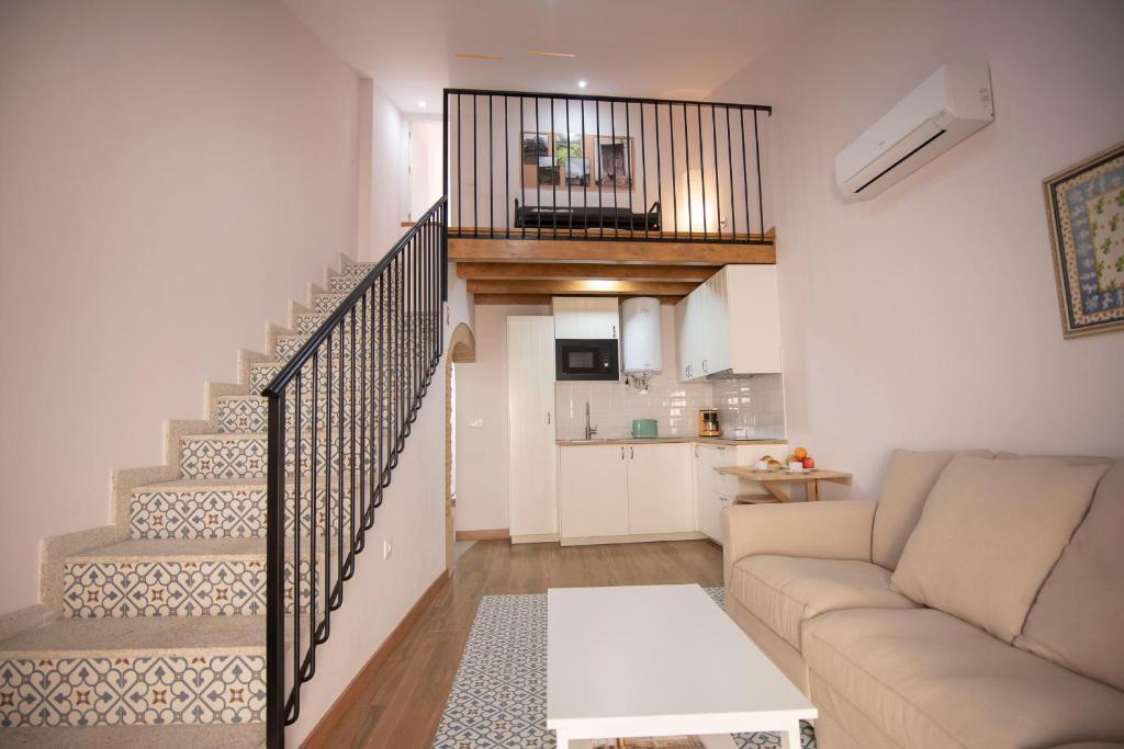 ein Wohnzimmer mit einem Sofa und einer Treppe in der Unterkunft Apartamento Dúplex Casco Antiguo AT Postigo 20 in Cáceres
