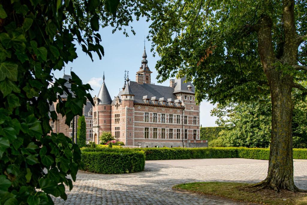 un antiguo castillo con un árbol en primer plano en Kasteel van Ordingen, en Sint-Truiden