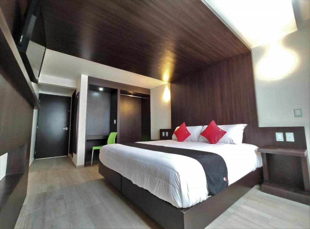 1 dormitorio con 1 cama grande con almohadas rojas en Hotel La Estancia Zacatlan, en Zacatlán