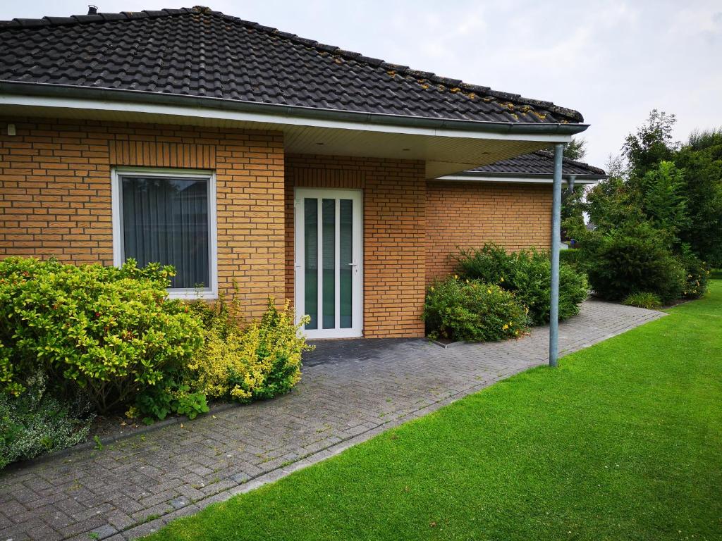 a brick house with a green lawn in front of it at Ferienwohnung Pewsum in Krummhörn