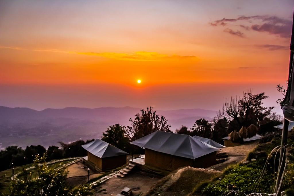 a sunset over a group of huts on a hill at CBB - Camp Bir Billing in Bīr