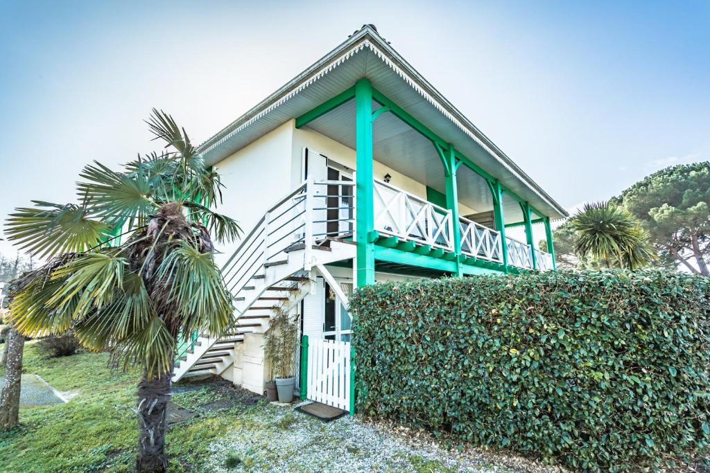 une maison avec une parure verte et un palmier dans l'établissement Sanguinet bel appartement 4 à 6 couchages plein centre ville proche commerces et lac, à Sanguinet