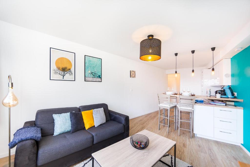 uma sala de estar com um sofá e uma cozinha em SPLENDIDE APPARTEMENT RENNES CENTRE + PARKING em Rennes