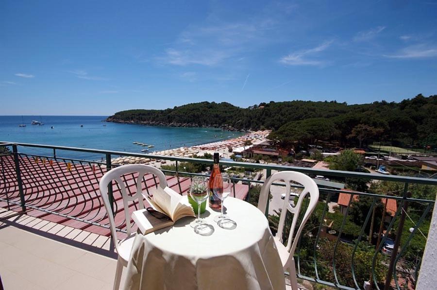 a table with wine glasses and a book on a balcony at Hotel Alma in Campo nell'Elba
