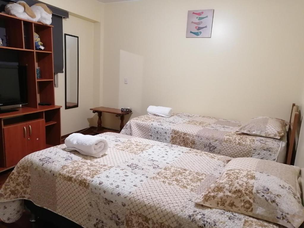 2 bedden in een kamer met een tv en een nachtkastje bij Casa Marite in Lima