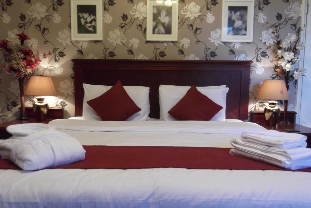 a bedroom with a large bed with white sheets and red pillows at The Ship Inn in London