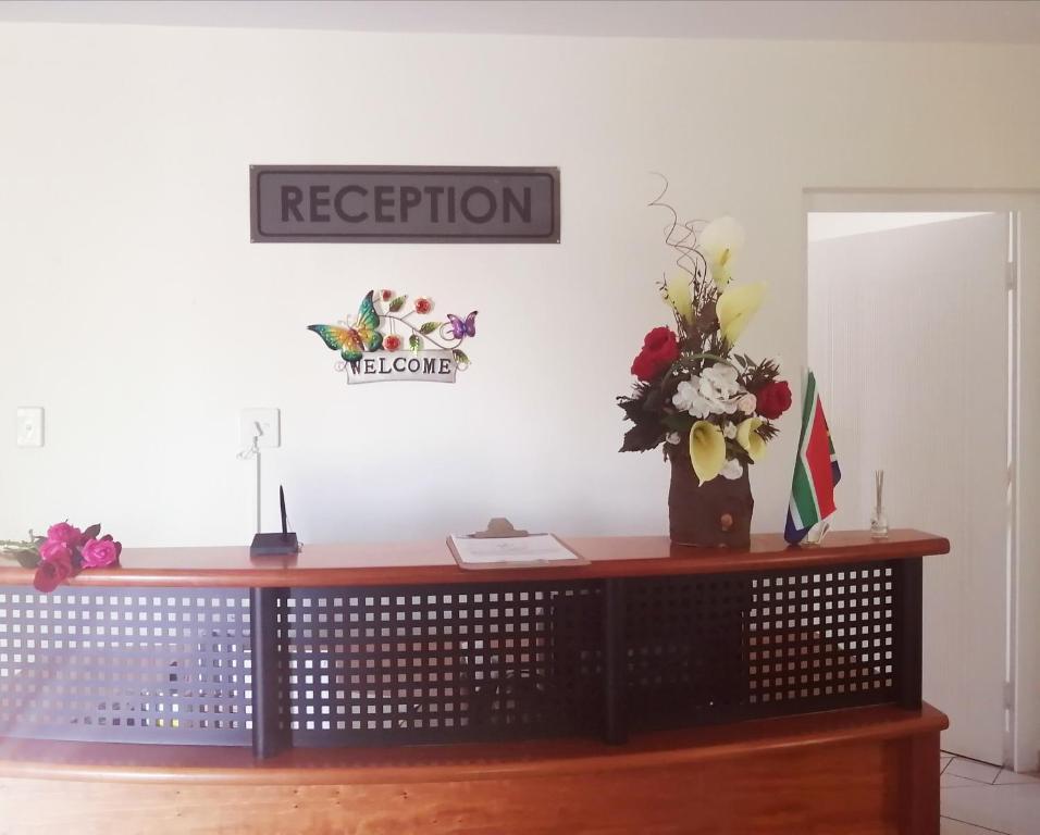 een bureau met een vaas met bloemen erop bij Hilton Gardens Guesthouse in Richards Bay