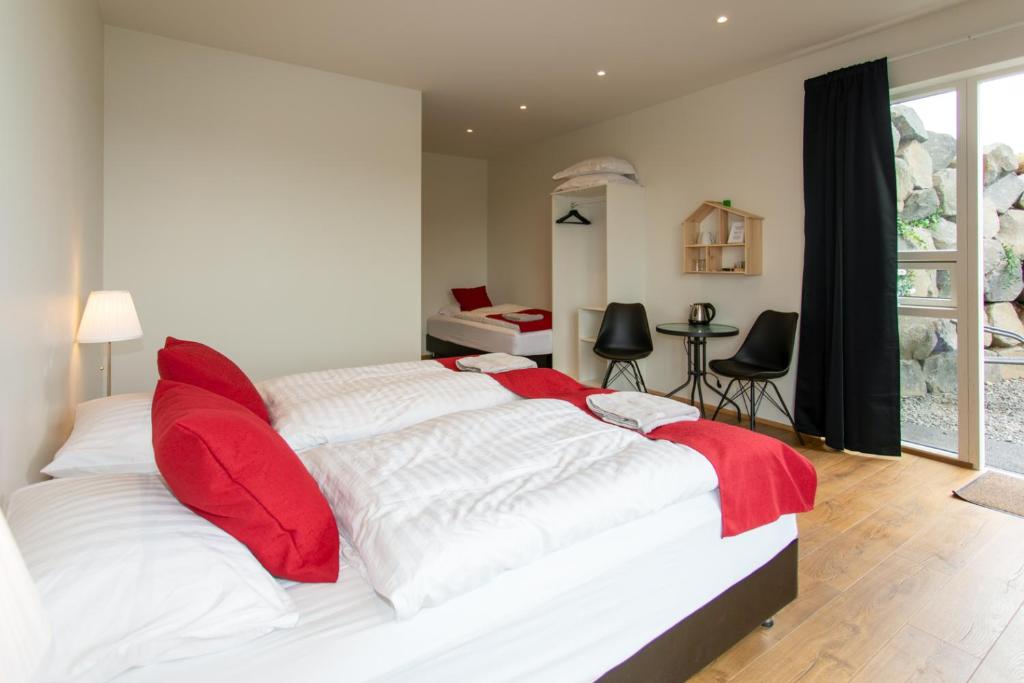 a bedroom with a large white bed with red pillows at Guesthouse Fludir in Fludir