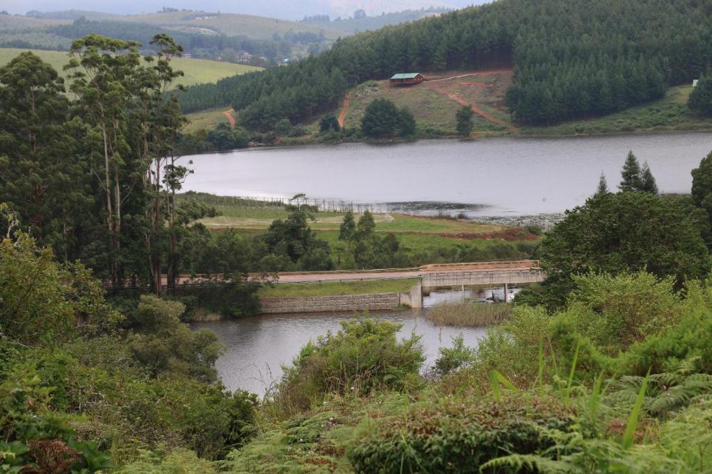 a bridge over a river next to a lake at Lakeview Cottages in Haenertsburg