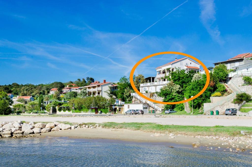 um círculo laranja numa praia com casas ao fundo em Apartments Albina em Lopar