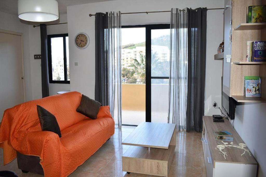 ein Wohnzimmer mit einem orangenen Sofa und einem Tisch in der Unterkunft Cesca Apartments - Marsalforn, GOZO in Marsalforn