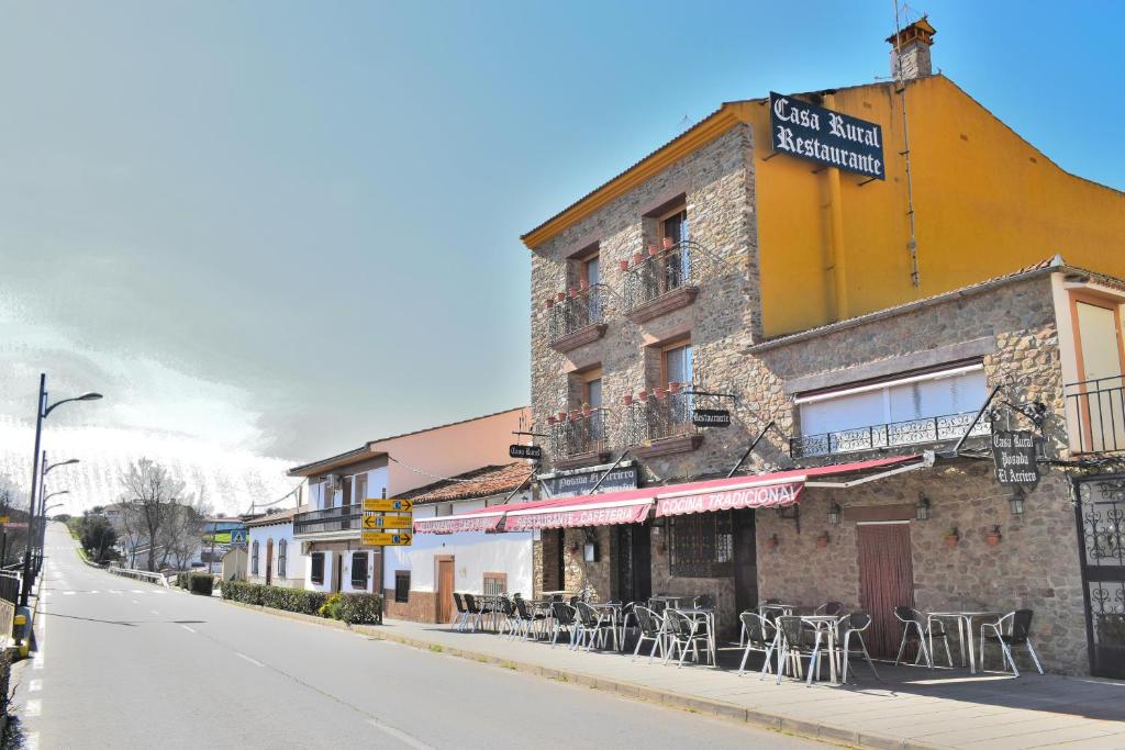 a building with tables and chairs on a street at POSADA EL ARRIERO in Torrejón el Rubio