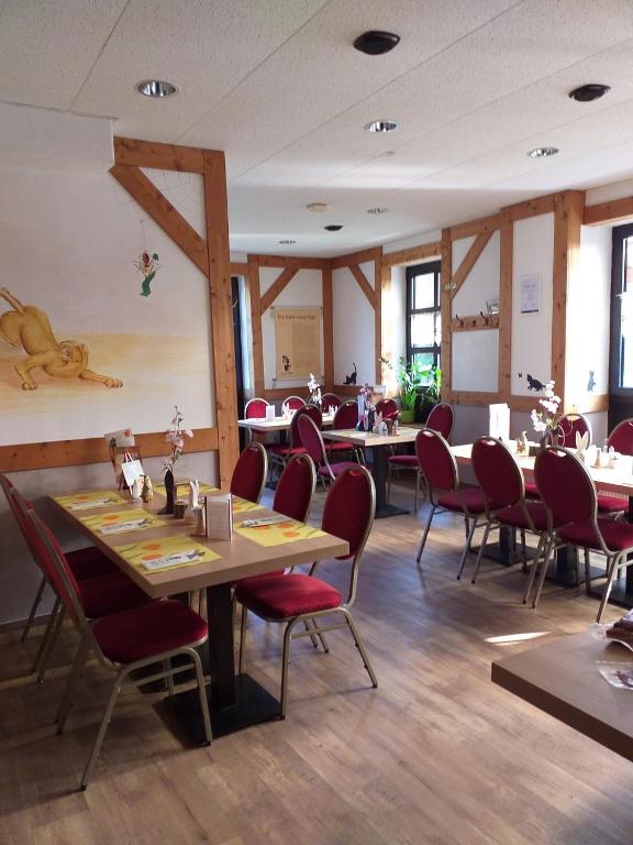 a dining room with tables and red chairs at Pension &amp; Gasthaus Kattenstieg in Kattenstiegs-Mühle